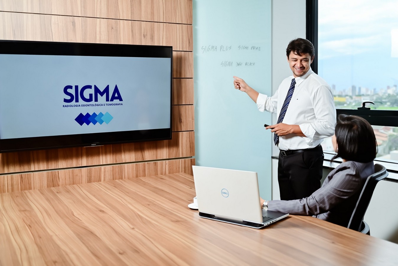 Equipe da Sigma em reunião de planejamento diante do logotipo da clínica.