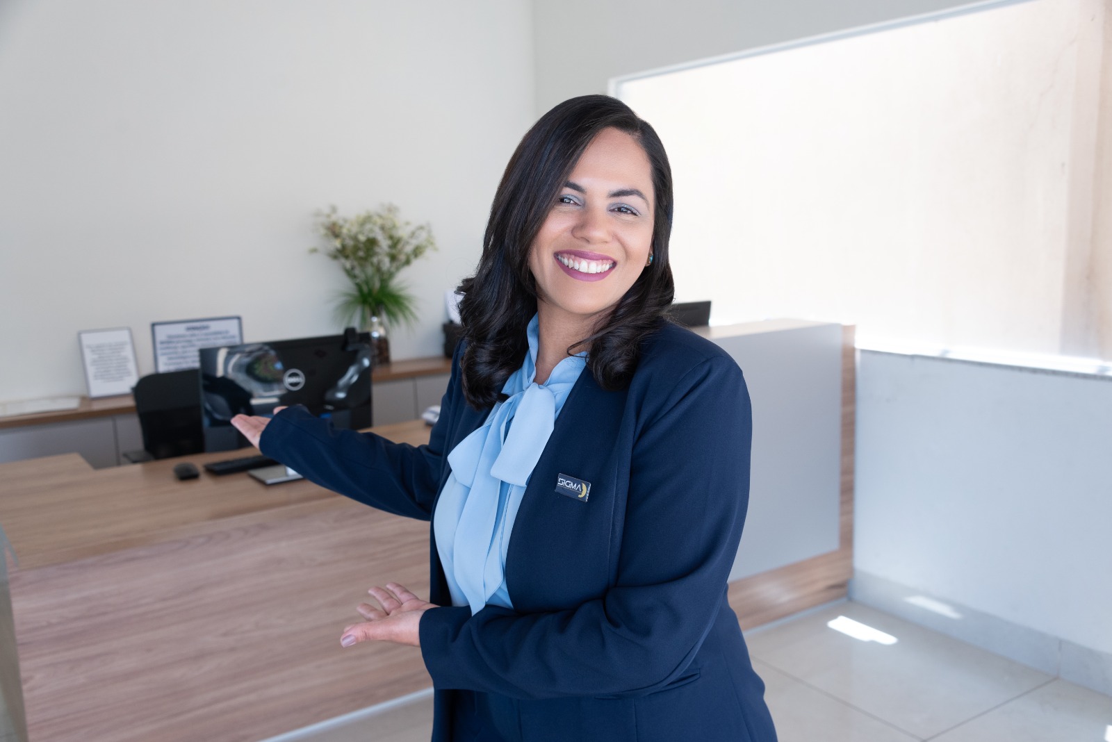 Recepcionista da Sigma sorrindo e apresentando a recepção da clínica.